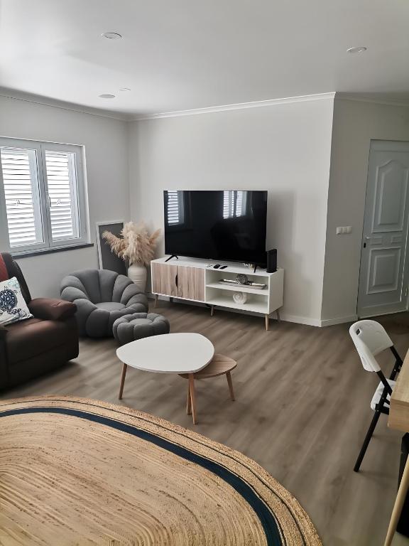 a living room with a tv and a couch and a table at Casa do Carapacho in Luz