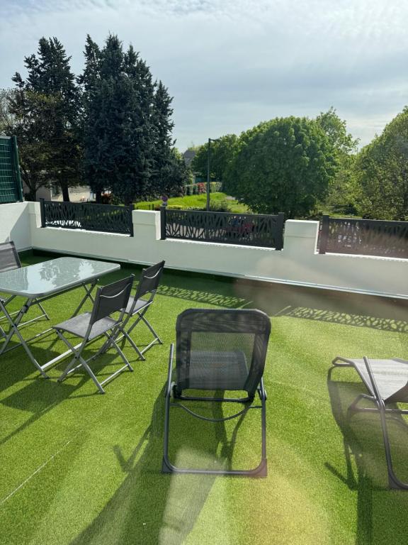 a patio with chairs and a table on the grass at Appart 2 morangis in Morangis