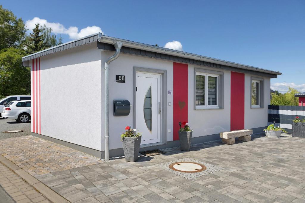 a small white and red building with a door at Pension Haus Leni am Schwanenteich in Mühlhausen