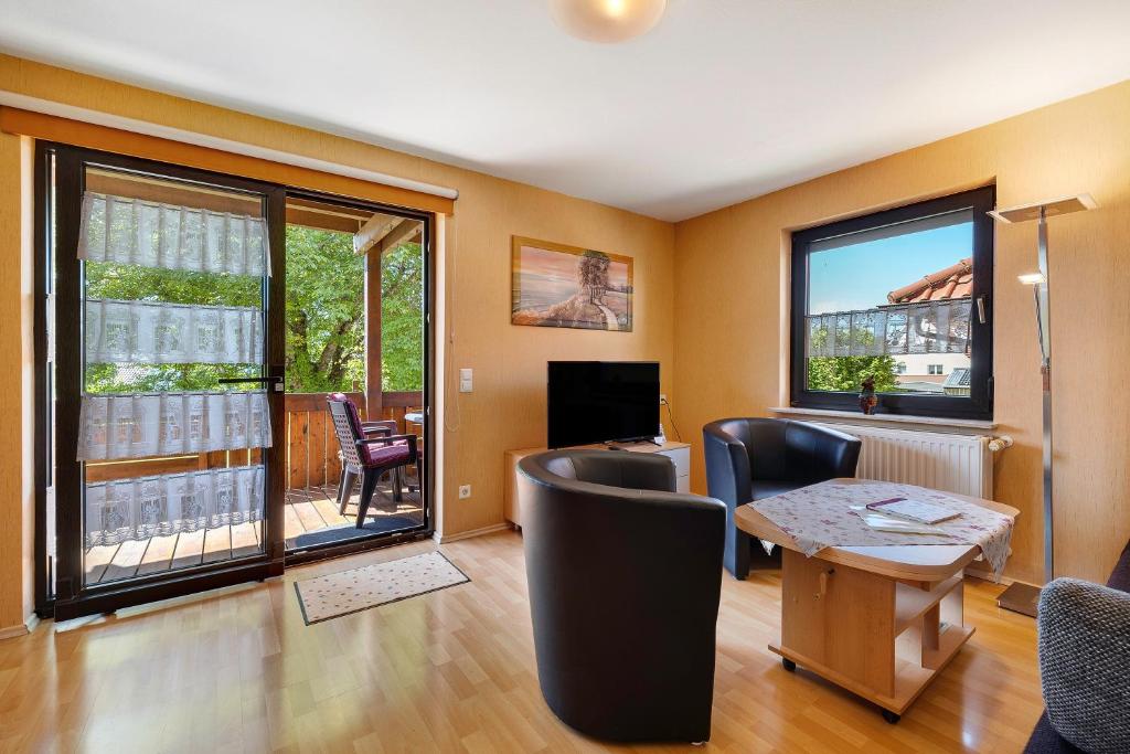 a living room with a table and chairs and windows at Ferienwohnung Eleonore in Meßstetten