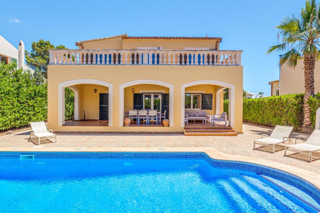 a villa with a swimming pool in front of a house at Villa Paula in Sa Ràpita
