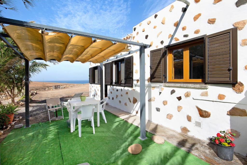 a patio with a table and chairs and a view of the ocean at Casa la solapa in Pájara