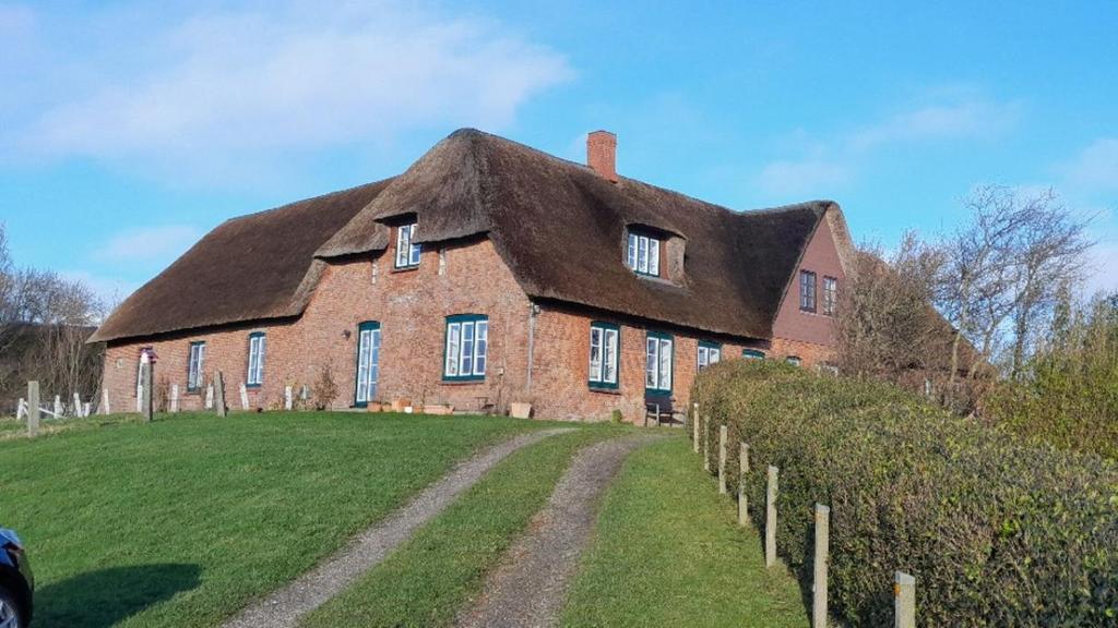 a large red brick house with a thatched roof at Fewo Op de Warft in Pellworm