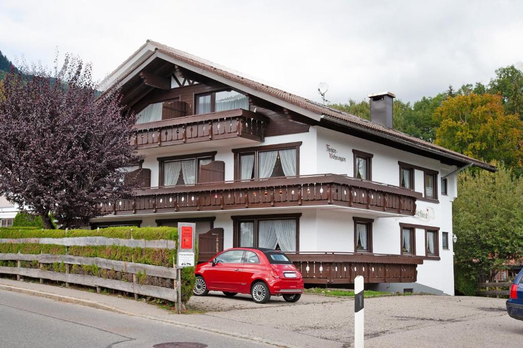 Ein rotes Auto parkte vor einem Haus in der Unterkunft Obermaiselstein in Obermaiselstein