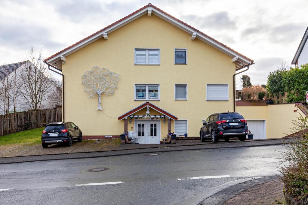 a yellow house with two cars parked in the driveway at App und Fewos Wolf in Usingen