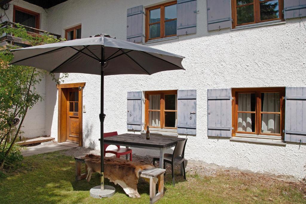 a table with an umbrella in front of a house at Alpenchalet Pfronten in Pfronten