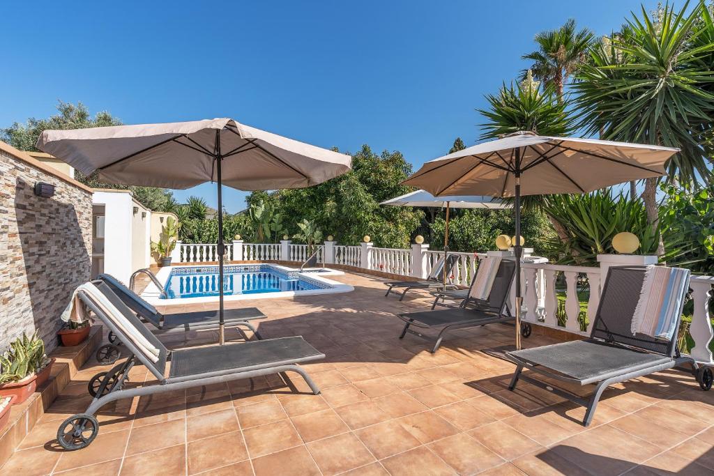 a patio with two umbrellas and a swimming pool at El Amanecer in Motril