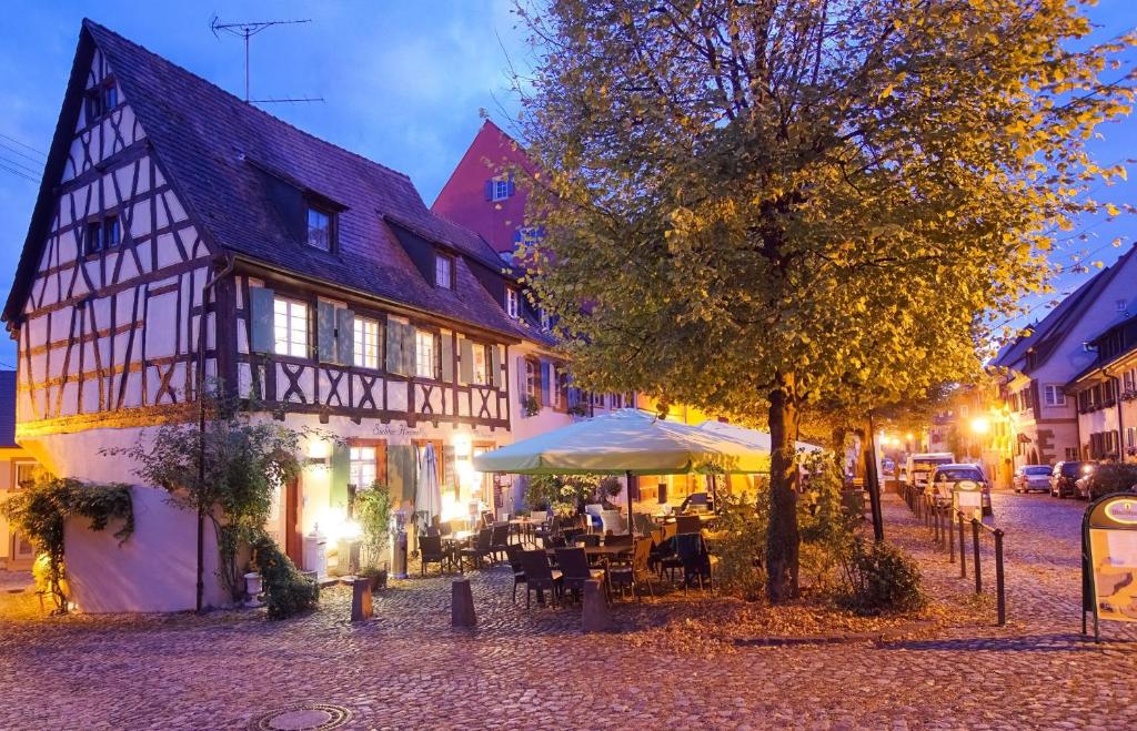 a street with a building and tables and a tree at Gästehaus Siebter Himmel in Burkheim