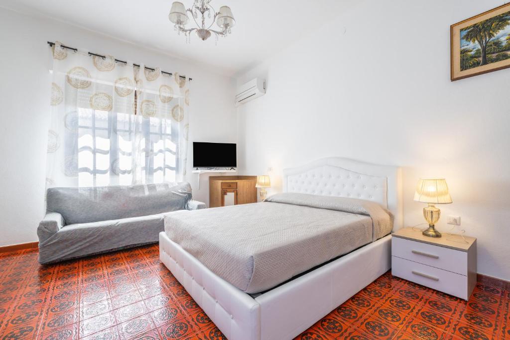 a white bedroom with a bed and a chair at Il Faro in Sarroch