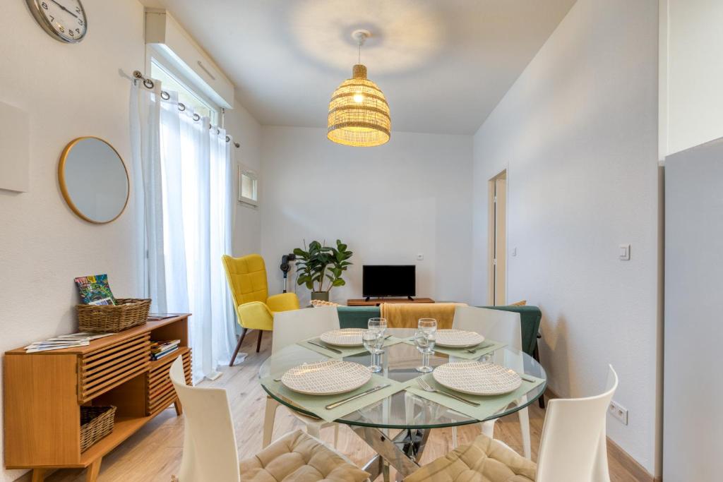 a dining room with a glass table and chairs at Le Voltaire pour 4 in Sète