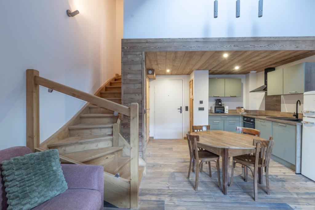a kitchen and dining room with a wooden table and stairs at Les Petits Loups in Morillon