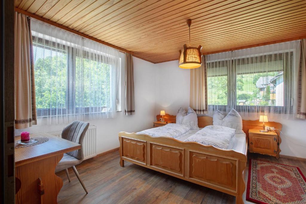 a bedroom with a bed and a desk and windows at Am Wehrastrand App Pr in Todtmoos