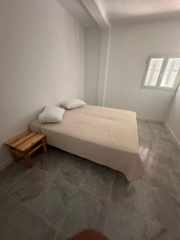 a white bedroom with a bed and a table at Appartement melita aéroport in Mellita