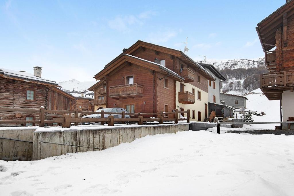 a log cabin in the snow with a fence at Appartamento Vacanze Matteo in Livigno