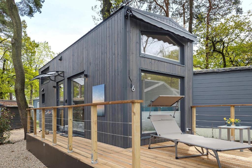 a black tiny house with a chair on a deck at Tiny House Nr 6 in Schwielowsee
