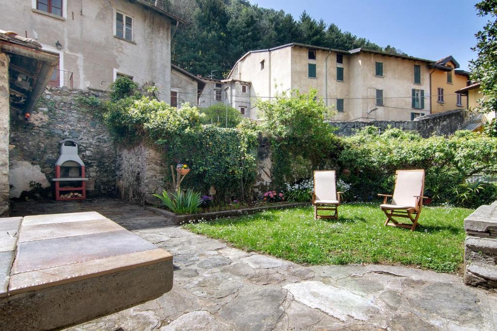 due sedie sedute in un cortile accanto a un edificio di Dongo Garden a Dongo