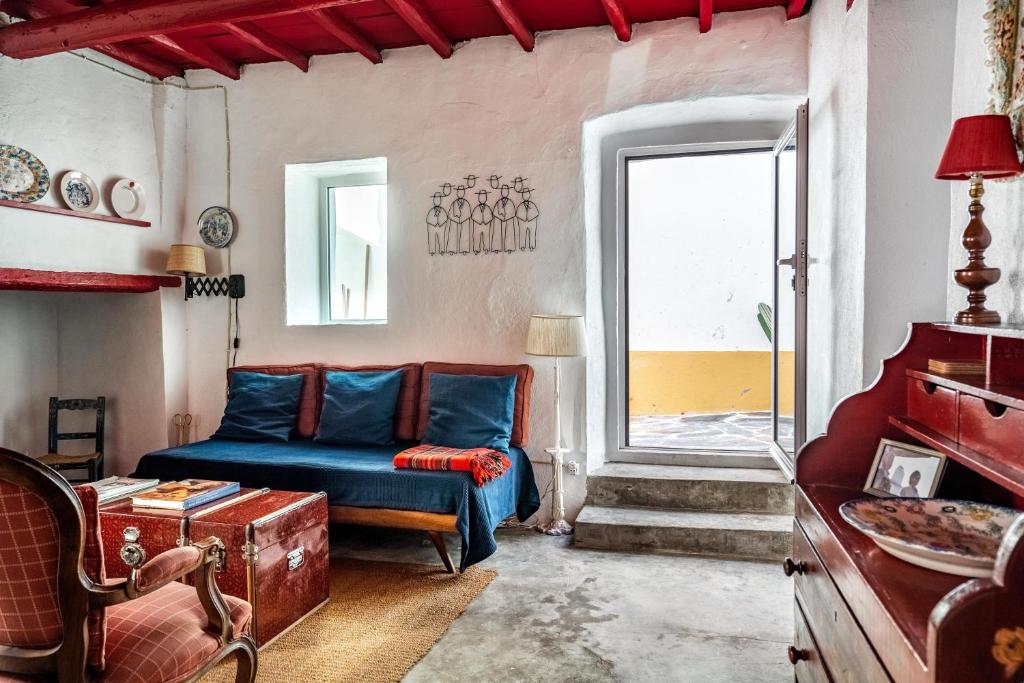 a living room with a blue couch and a window at Casa do Pelourinho in Avis