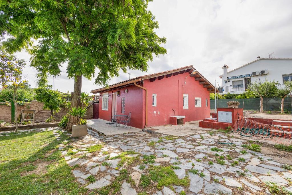 a red house with a tree in a yard at Cal Jaume in Masquefa