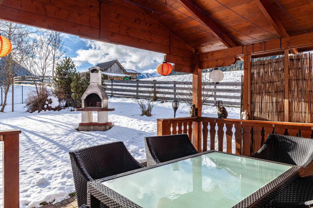 a wooden deck with a table and chairs in the snow at Ferienhaus Wechner in Häselgehr