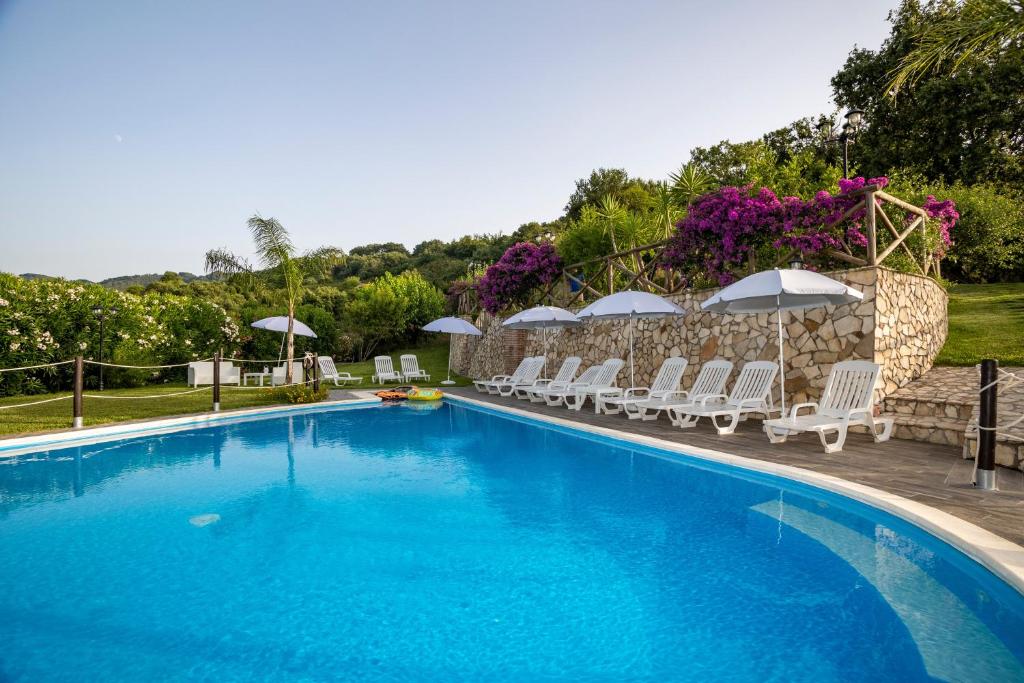 a large swimming pool with chairs and umbrellas at Arcaloro Resort Rooms in SantʼAngelo di Brolo