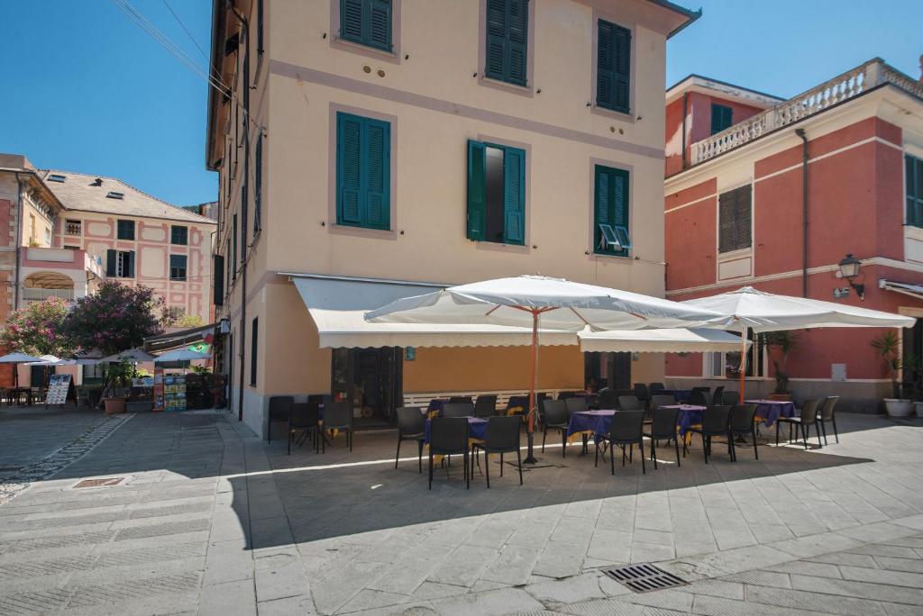 a patio with tables and chairs and umbrellas at Piazza 100 Croci in Bonassola