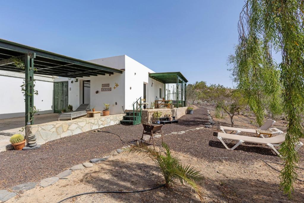 a house with two chairs and a couch in the yard at La Finca Las Estrellas in Tarajalejo