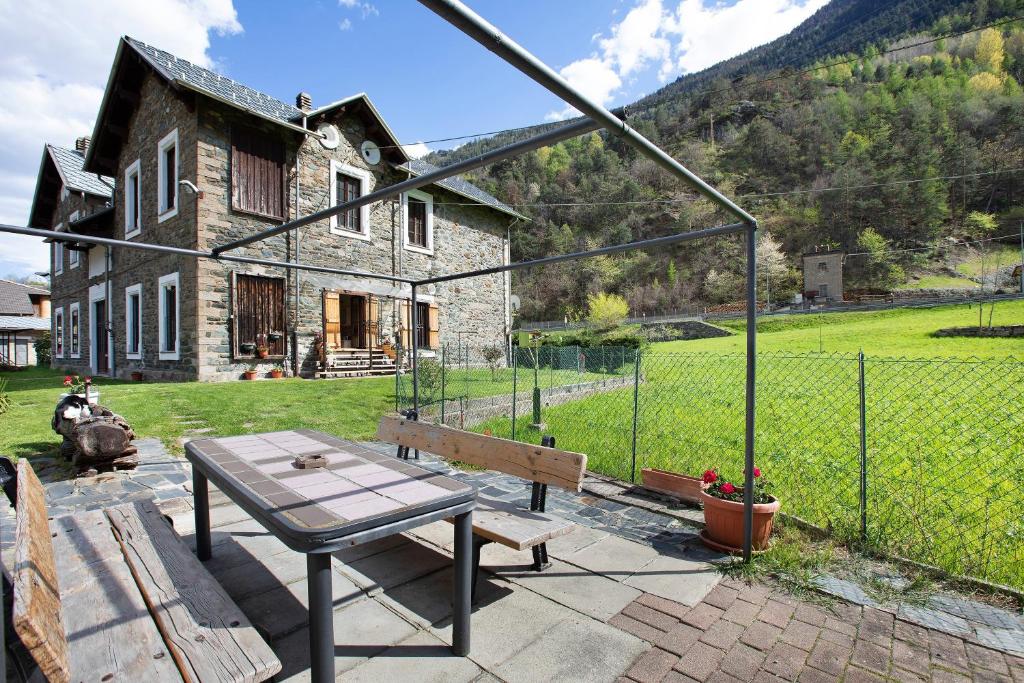 a patio with a table and bench in front of a house at Casa Tua - Avise in Avise