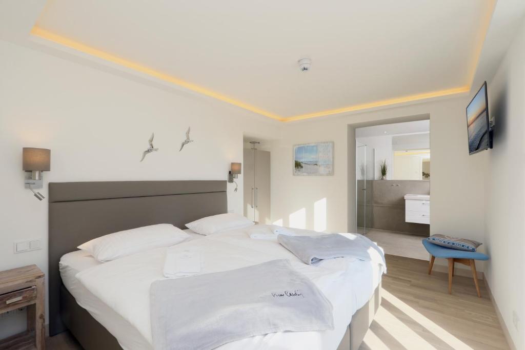 a bedroom with a large bed with white sheets at Gardensuite Binz in Binz