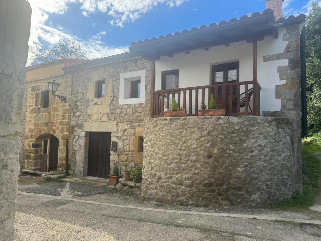 a stone house with a balcony with potted plants at Casa Eider in Rucandio