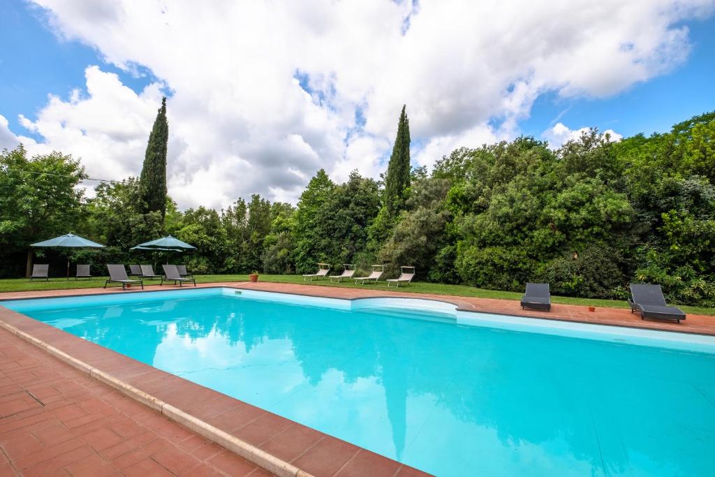 a swimming pool with blue water and trees at Rosaspina - Appartamento 4 in Capalbio