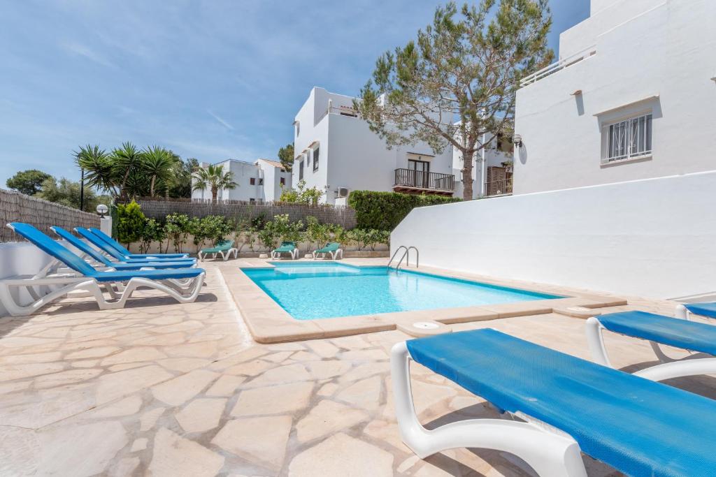 a villa with a swimming pool and blue chairs at Apartamentos Karin 2ºd in Cala d´Or