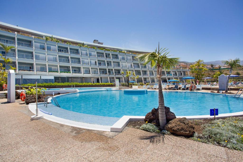 a swimming pool with a palm tree in front of a hotel at Casa Ana in Santa Úrsula