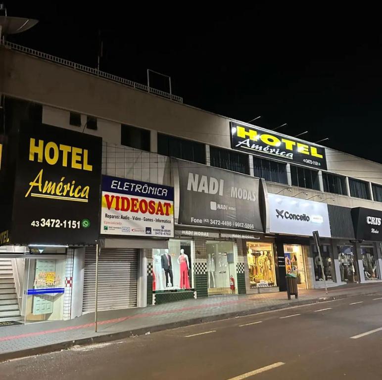 a building with many signs on the side of a street at Hotel América in Ivaiporã