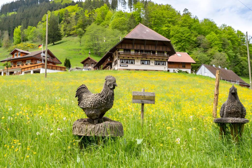 two statues of chickens in a field with a house at Josenhof in Wolfach