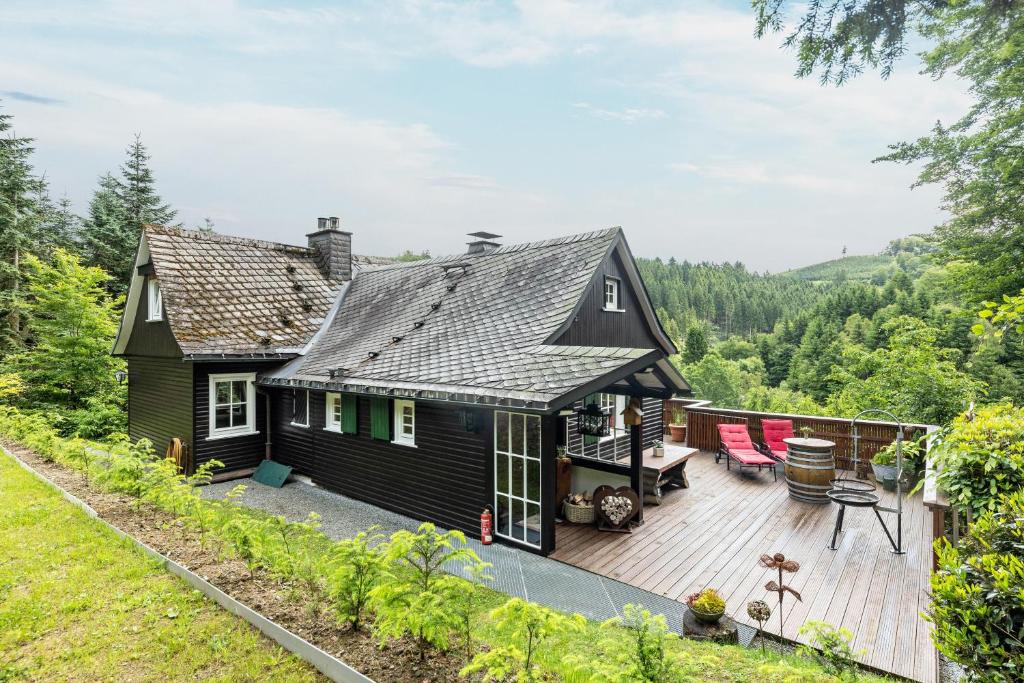 a black house with a deck with red chairs at Tannenhäuschen Sauerland in Schmallenberg