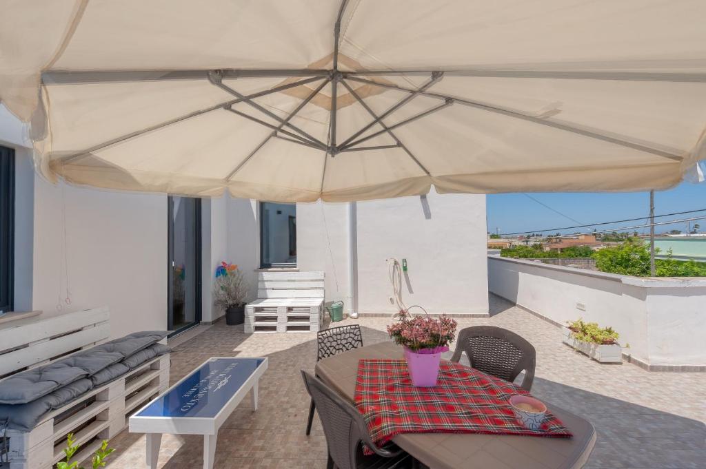 a patio with a table and a large umbrella at Meravigliosalento in Squinzano
