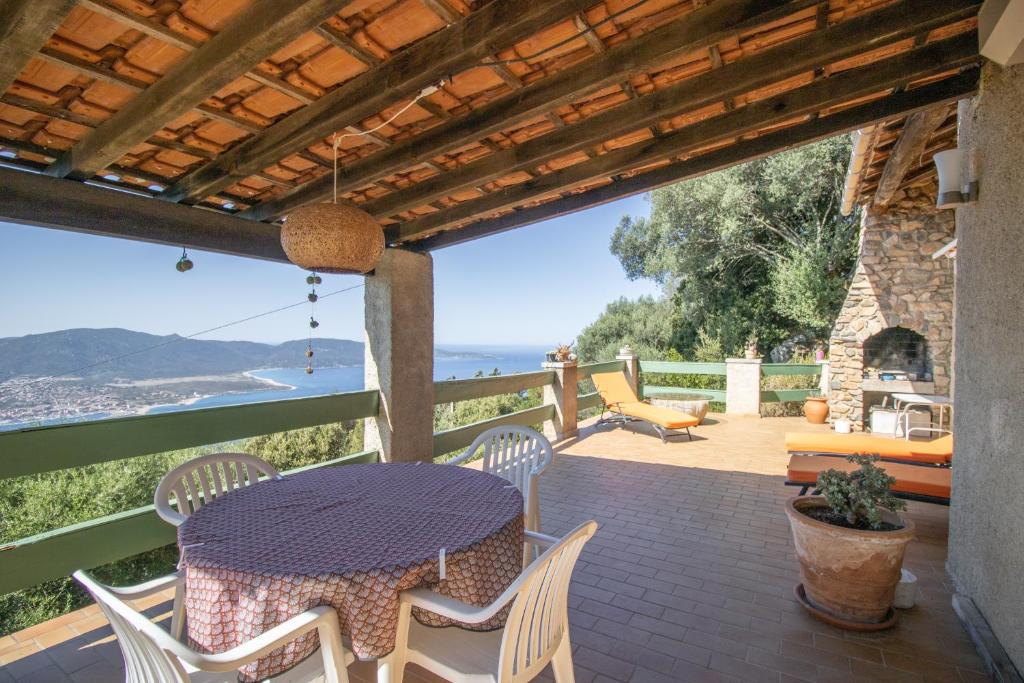 a table and chairs on a patio with a view of the ocean at Mon nid d'aigle in Olmeto
