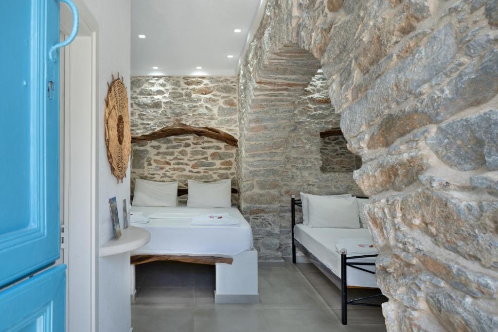 a room with two beds and a stone wall at Politimis Studio N6 in Amorgos