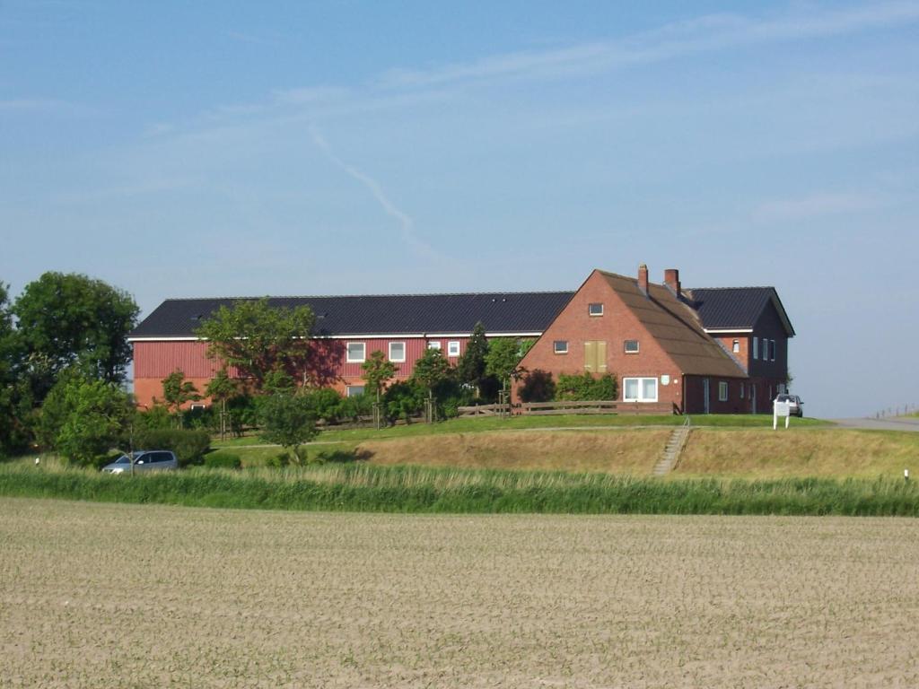 a house on a hill with a field in front at Ferienhof Dethlefsen in Pellworm