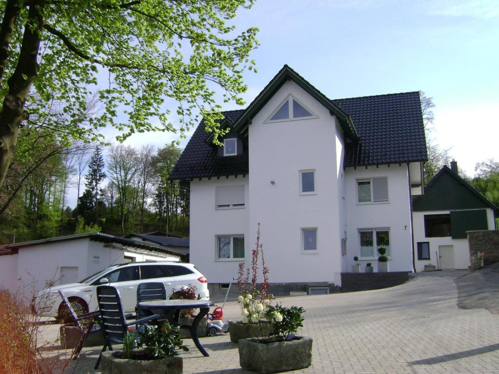 a white house with a car parked in front of it at Ferienwohnung Bock Feldmannshof in Drolshagen