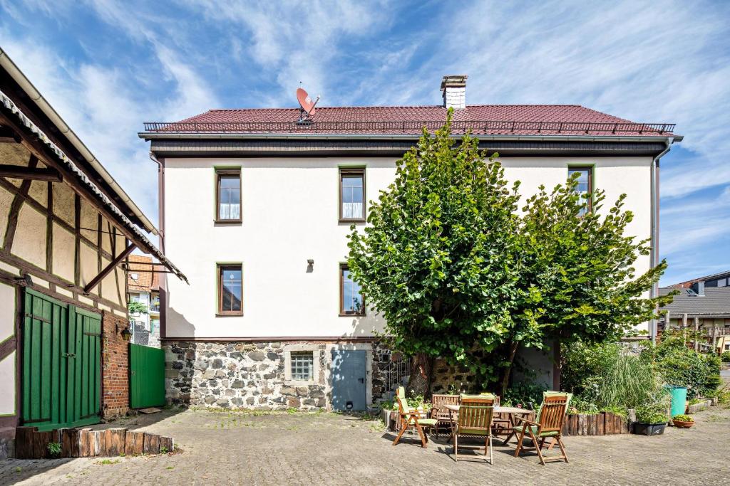 a large white building with chairs and a tree at Bachmanns Ferienwohnung 2 in Schotten