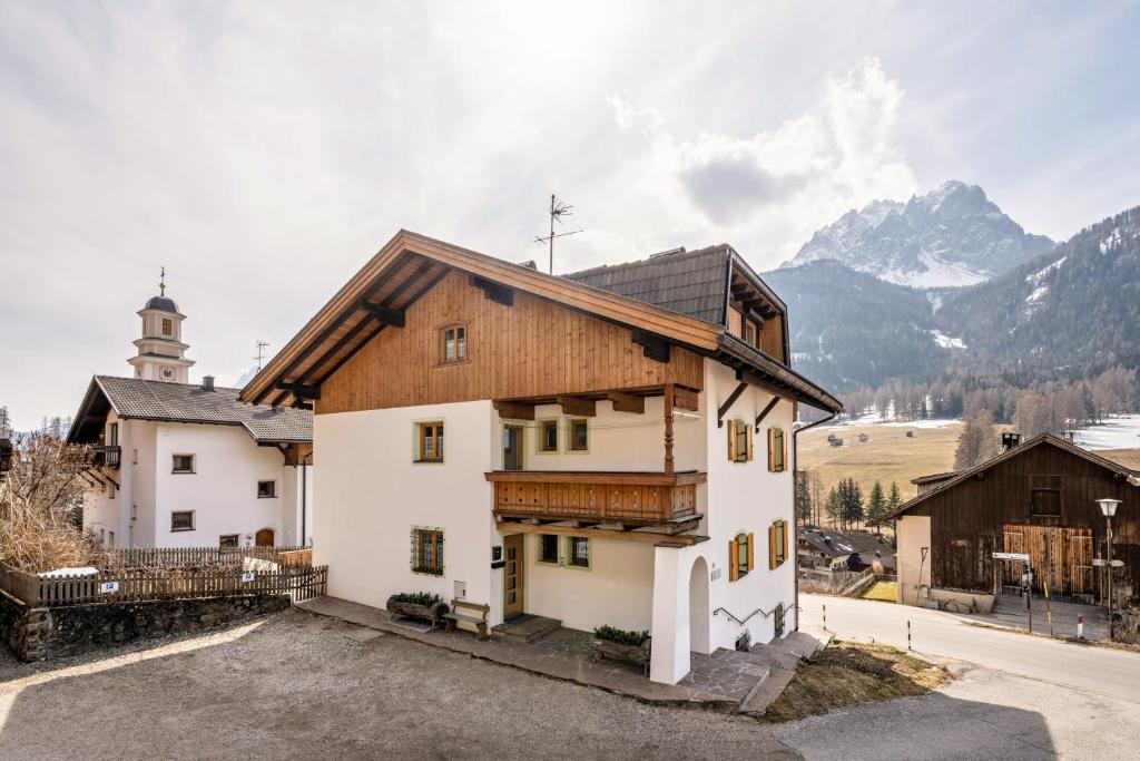 a house with a church and mountains in the background at Manuel's App Watschinger - Enzian in Sesto