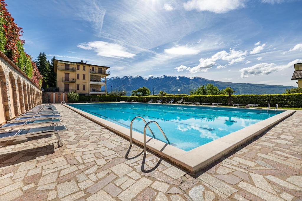 a large swimming pool with mountains in the background at Appartamento Alexander in Tignale