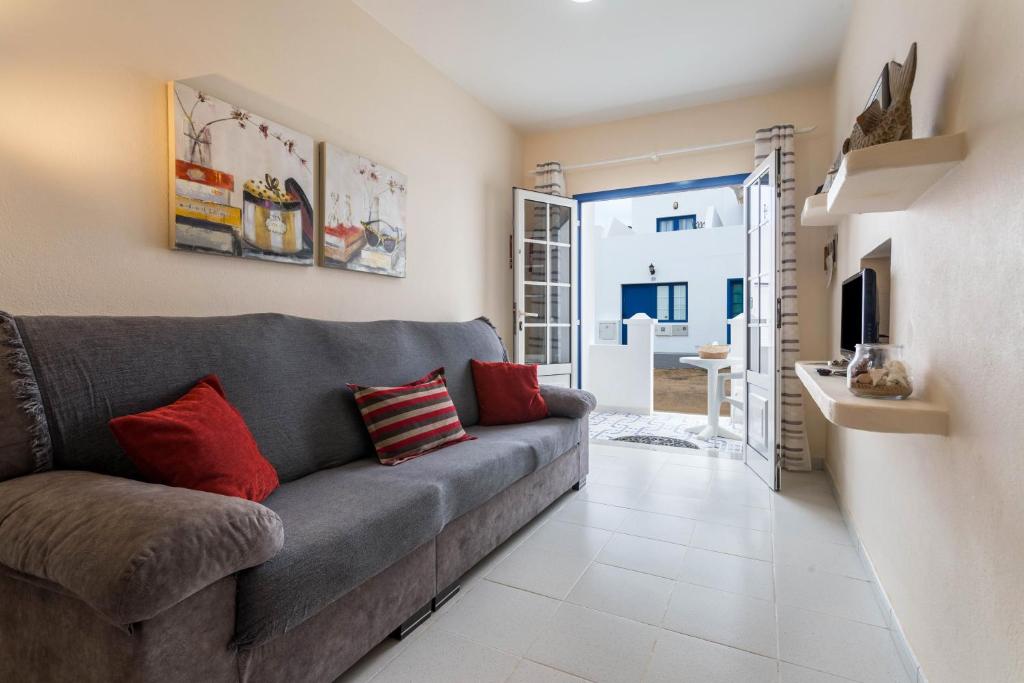 a living room with a gray couch and red pillows at El Sombrerito 4 in Caleta de Sebo