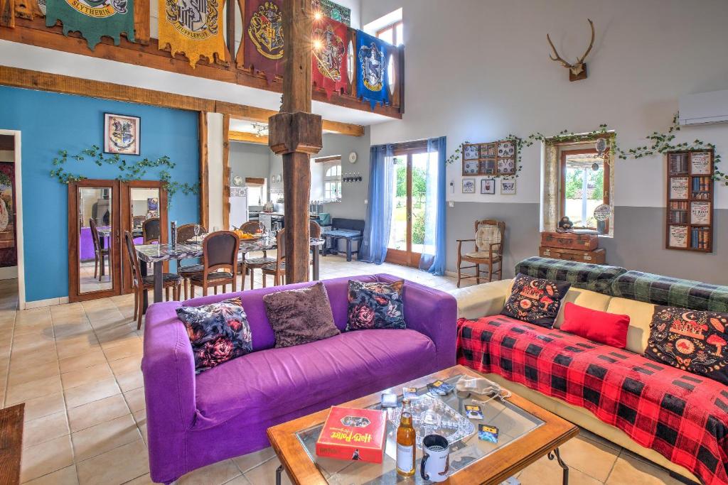 a living room with a purple couch and a table at Le Magicogite - Harry Potter in Larocal