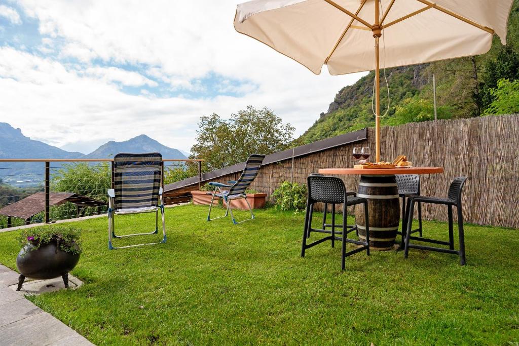a patio with a table and chairs and an umbrella at Maso Plocech App Vacanze in Pergine Valsugana