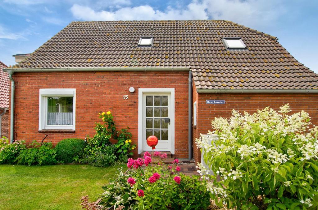 a red brick house with flowers in the yard at Huus Karoline in Junkersrott