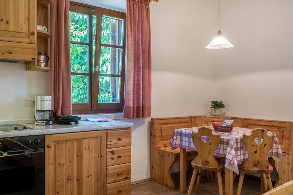 a kitchen with a table with chairs and a window at Sallrain Hof Monolokal 4 in Collalbo