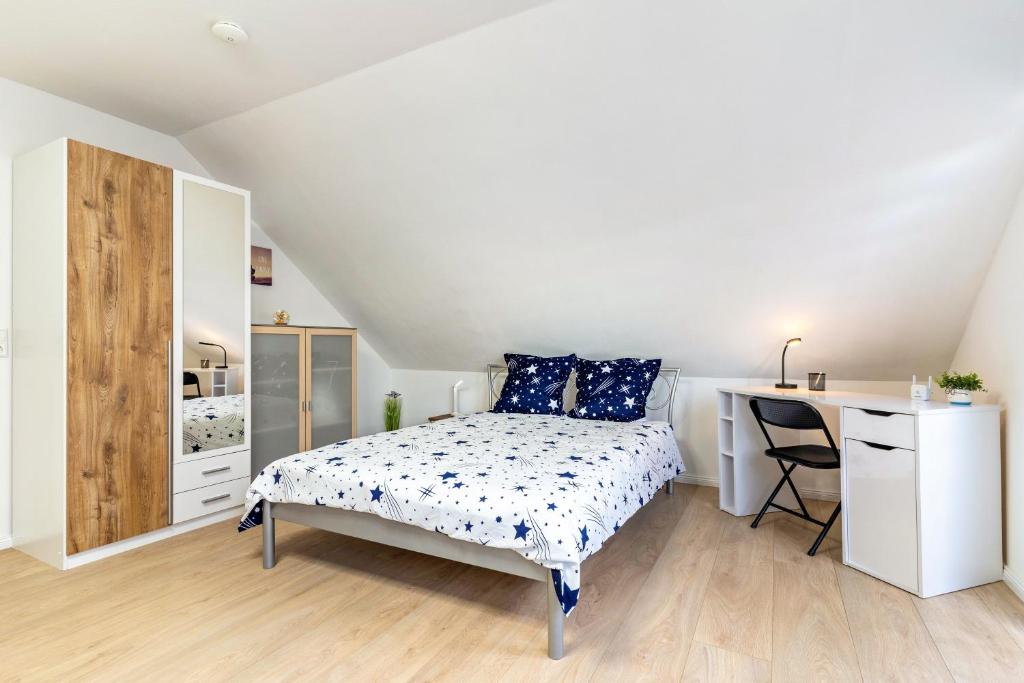a white bedroom with a bed and a desk at Ferienwohnung Sena in Weisweil