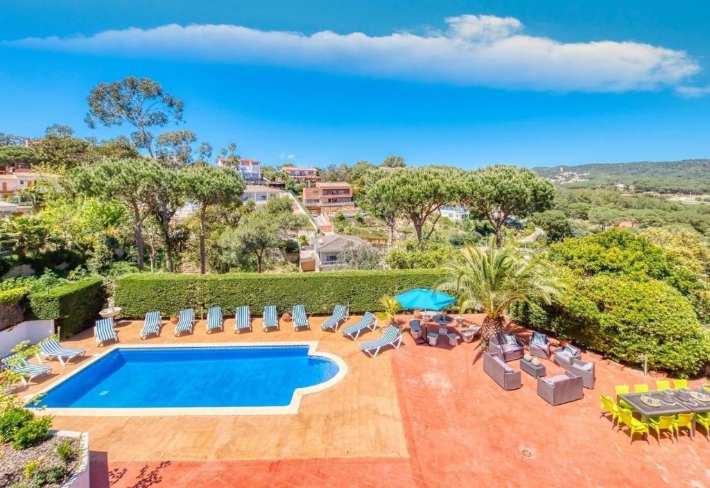an image of a swimming pool with chairs and a resort at Costacabana - Villa Jaruco in Lloret de Mar